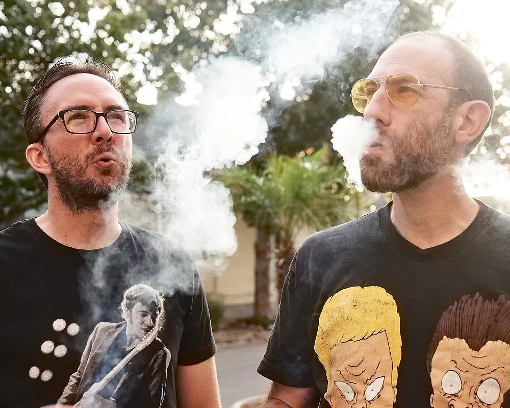 Comedian Ari Shaffir exhaling smoke while smoking with comedian Joe List of Tuesdays with Stories lighting a cigarette in a suit at comedian Mark Normand's wedding to Mae Planert in New Orleans. Find more about Joe at www.tuesdayspod.com/joe-list