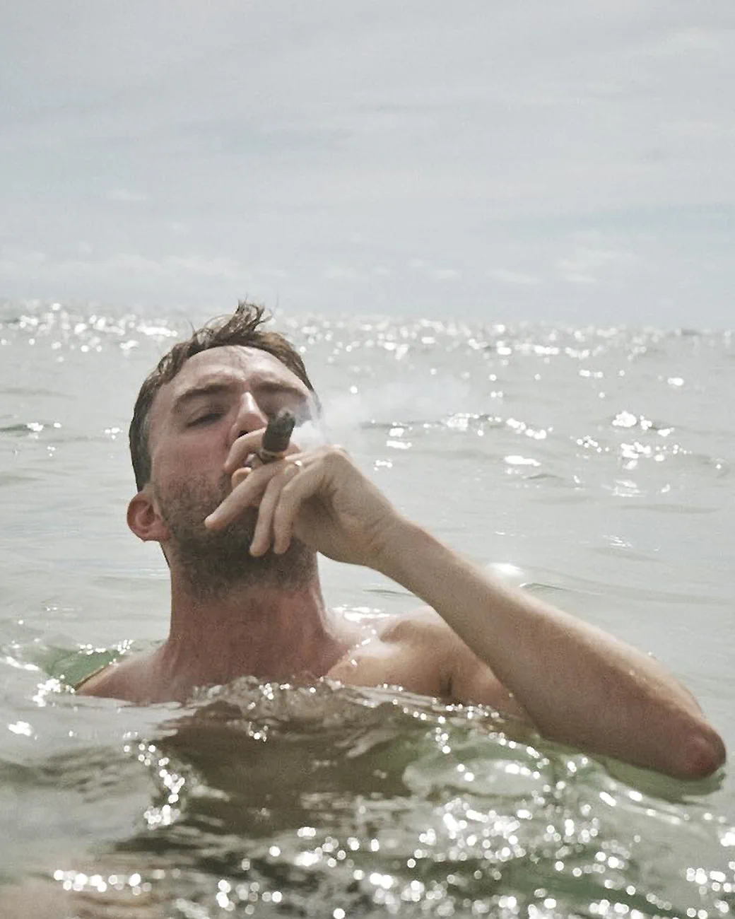 Comedian Joe List of Tuesdays with Stories smoking a cigar in the ocean. Find more about Joe at www.tuesdayspod.com/joe-list