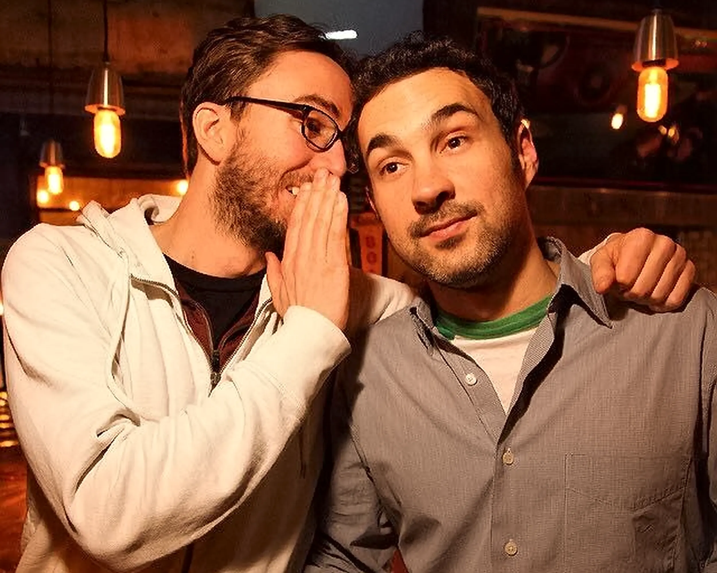 Comedian Joe List whispering to comedian Mark Normand, hosts of Tuesdays with Stories. Find Mark Normand Tour Dates and Joe List Tour Dates at www.tuesdayspod.com/find-a-show