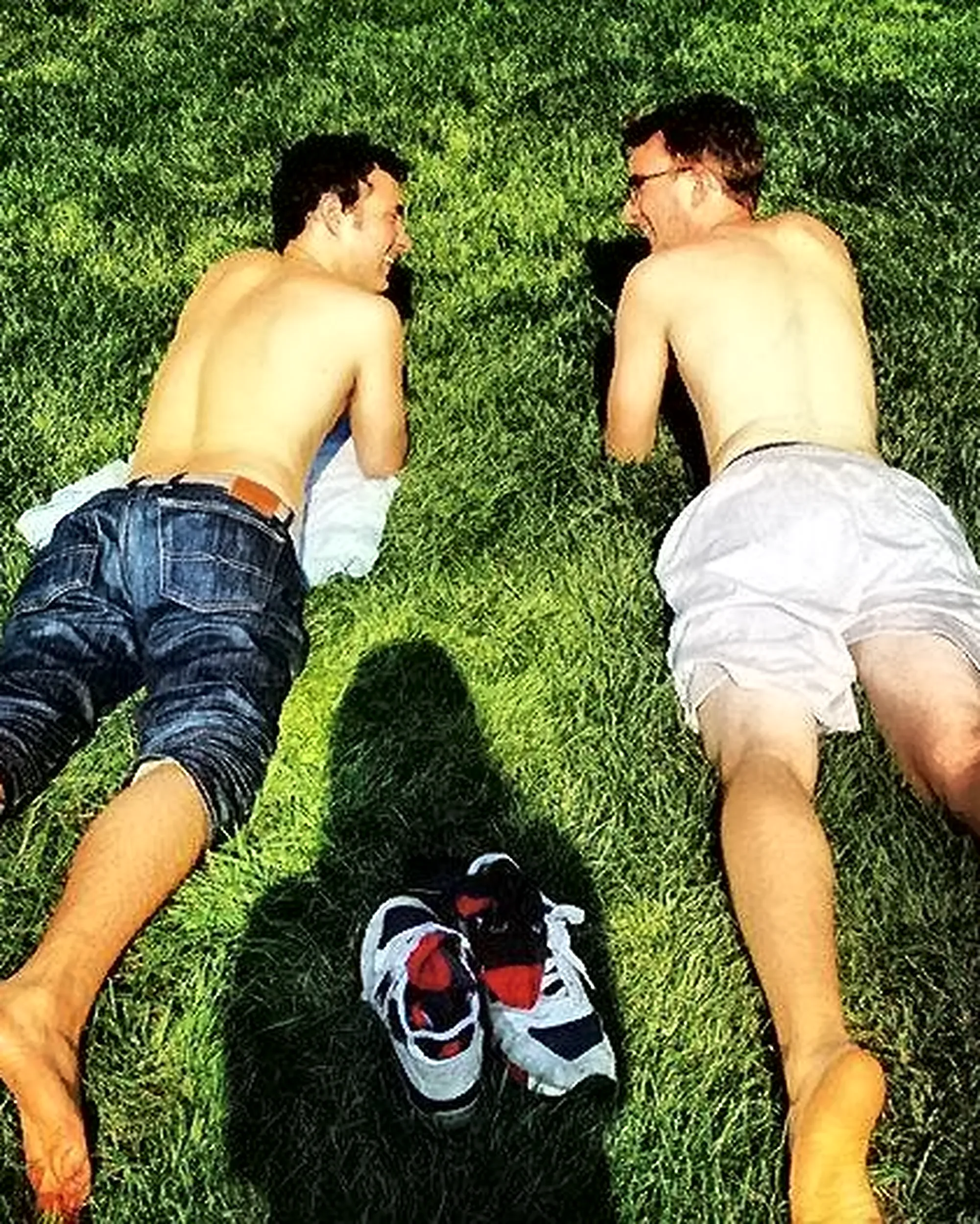 Comedians Mark Normand and Joe List of Tuesdays with Stories sunbathing on the grass, shirtless. Find Mark Normand Tour Dates and Joe List Tour Dates at www.tuesdayspod.com/find-a-show
