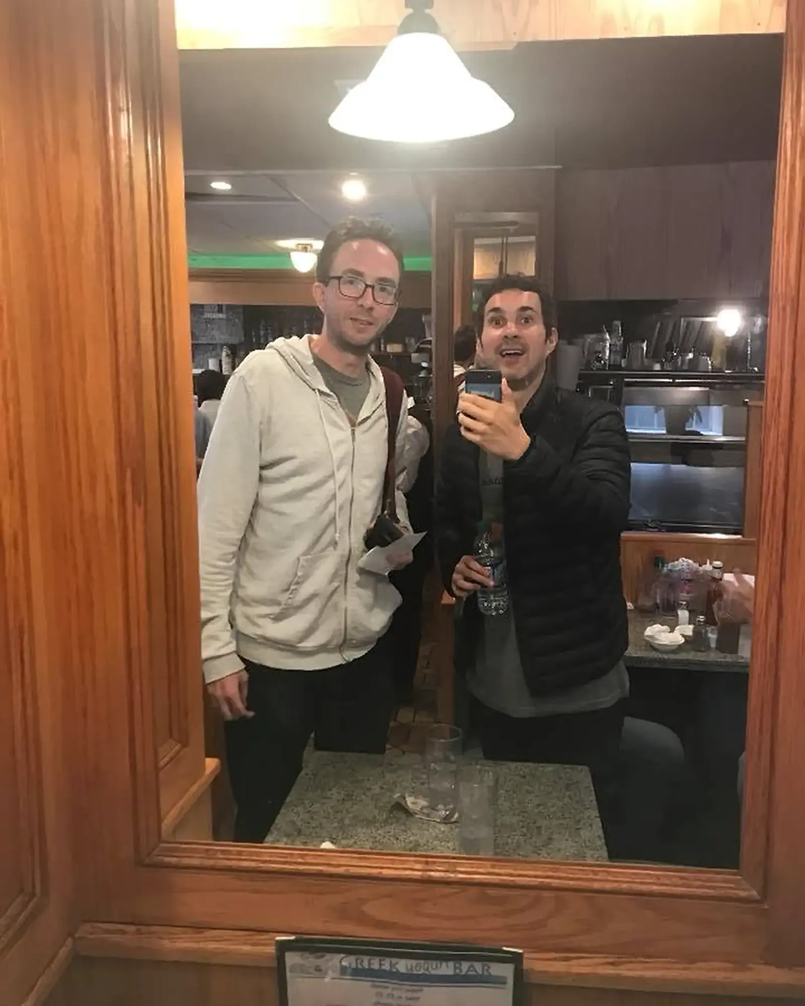 Comedians Mark Normand and Joe List of Tuesdays with Stories at a diner, taking a mirror picture. Find Mark Normand Tour Dates and Joe List Tour Dates at www.tuesdayspod.com/find-a-show