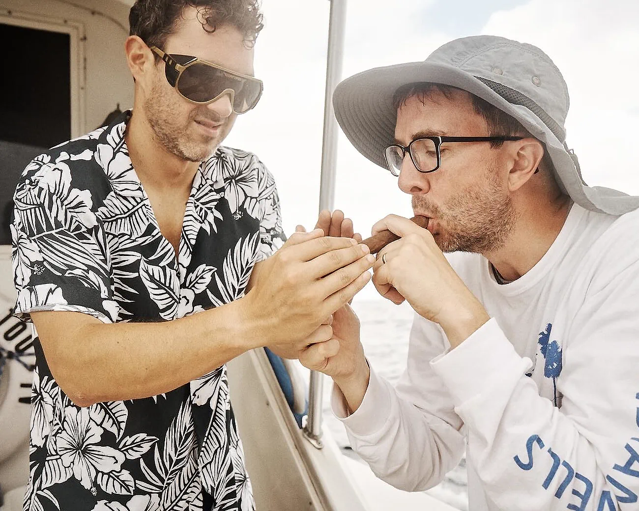 Comedians Mark Normand and Joe List of Tuesdays with Stories smoking a cigar on a fishing boat in the ocean. Find more Tuesdays with Stories photos at www.tuesdayspod.com/photos